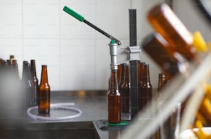 Línea de producción de bebidas artesanales en fábrica, cervecería y pequeña empresa, cuarentena covid-19. Botellas llenas y vacías para equipos de cerveza, cerveza y taponado en el interior de la planta, nadie, espacio libre, maqueta