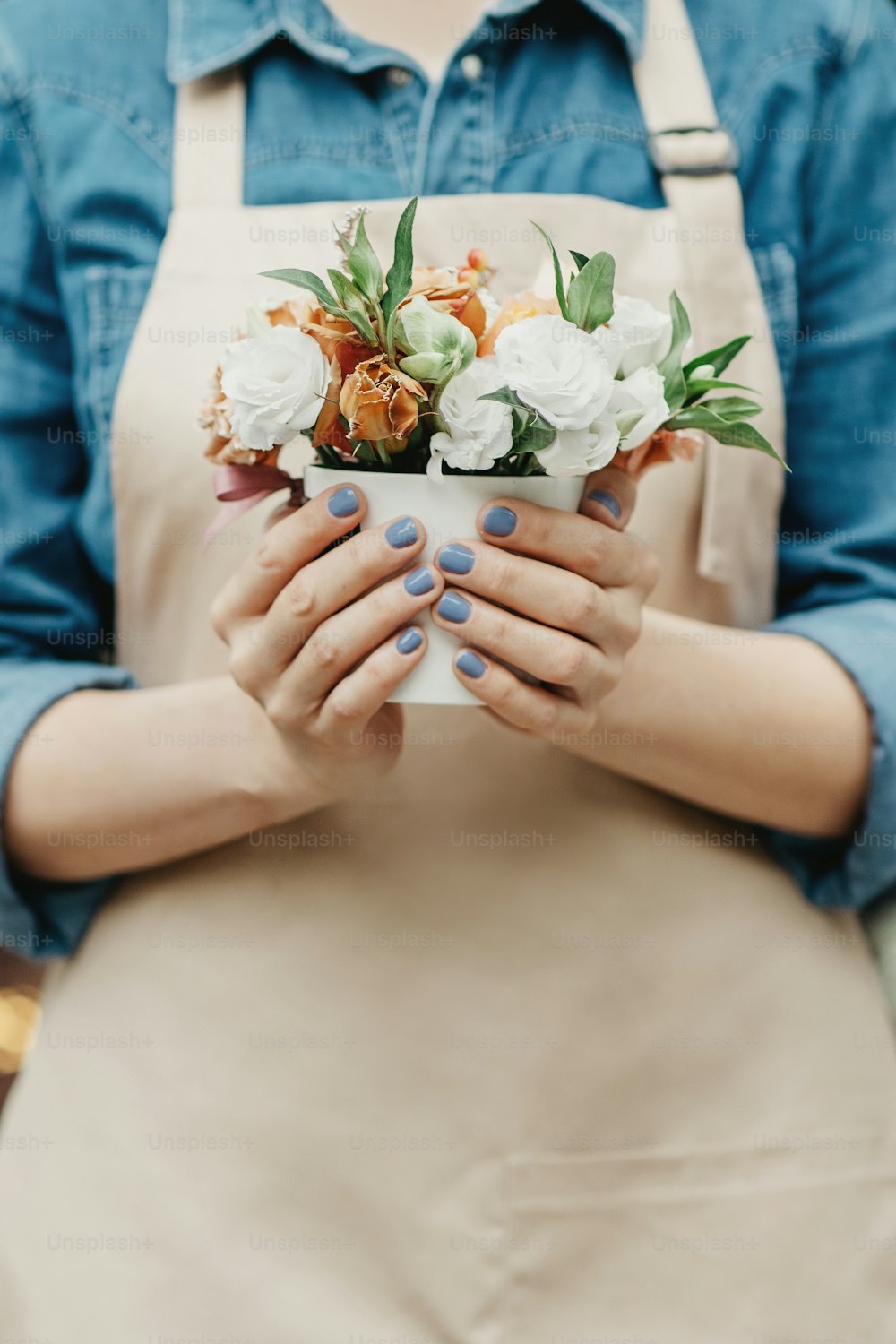Small business, flower shop, decor studio and outdoor work. Online order for client and floristic job. Millennial lady in apron holding stylish bouquet in floral studio, close up, cropped, vertical
