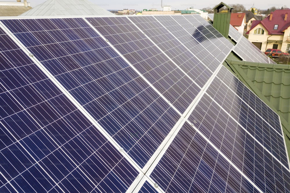 Superficie de primer plano del sistema de paneles fotovoltaicos solares azules brillantes en el techo del edificio. Concepto de producción de energía verde ecológica renovable.