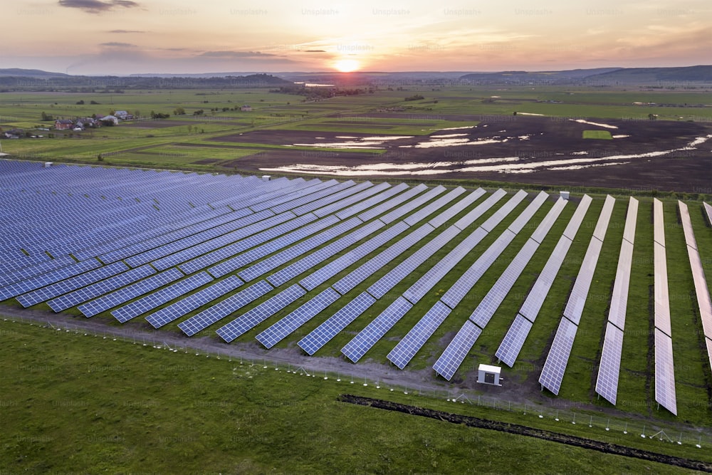 Blaues Solar-Photovoltaik-Panel-System, das erneuerbare saubere Energie in ländlicher Landschaft und untergehendem Sonnenhintergrund erzeugt.