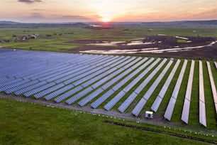 Sistema de painéis solares fotovoltaicos azuis que produzem energia limpa renovável na paisagem rural e no fundo do sol poente.
