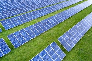 Surface of solar photo voltaic panels system producing renewable clean energy on green grass background.