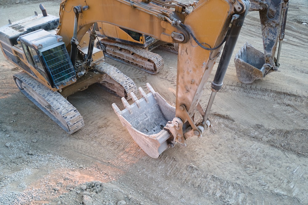 Open pit mining site of construction sand stone materials with excavator equipment for digging of gravel resources at quarry.