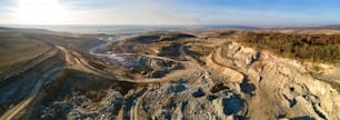 Aerial view of open pit mine of sandstone materials for construction industry with excavators and dump trucks. Heavy equipment in mining and production of useful minerals concept.