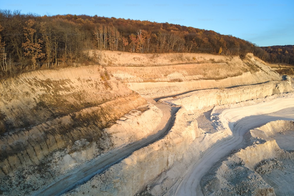 Luftaufnahme des Tagebaus von Sandsteinmaterialien für die Bauindustrie mit Baggern und Muldenkippern. Schweres Gerät im Bergbau und in der Produktion von nützlichen Mineralien.