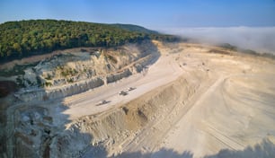 掘削機とダンプトラックを備えた建設業界向けの石灰岩材料抽出の露天掘り現場の空撮。