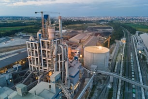 Vista aérea de la fábrica de cemento con estructura de planta de hormigón alto y grúas torre en el área de producción industrial por la noche. Fabricación y concepto de industria global.