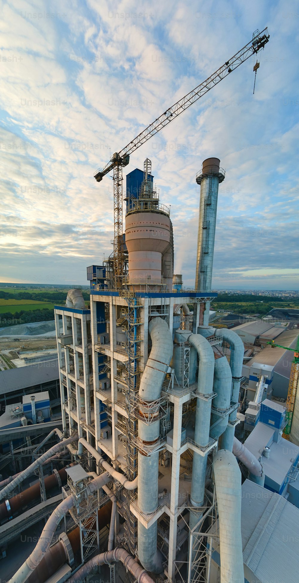 Aerial view of cement factory with high concrete plant structure and tower crane at industrial production site. Manufacture and global industry concept.