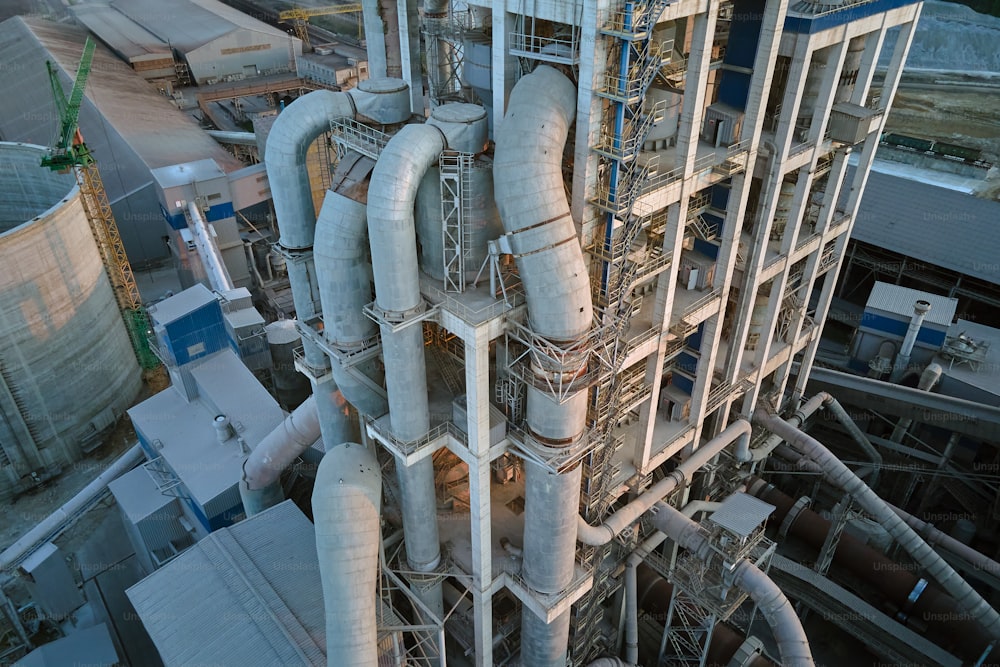 Aerial view of cement factory with high concrete plant structure and tower crane at industrial production site. Manufacture and global industry concept.