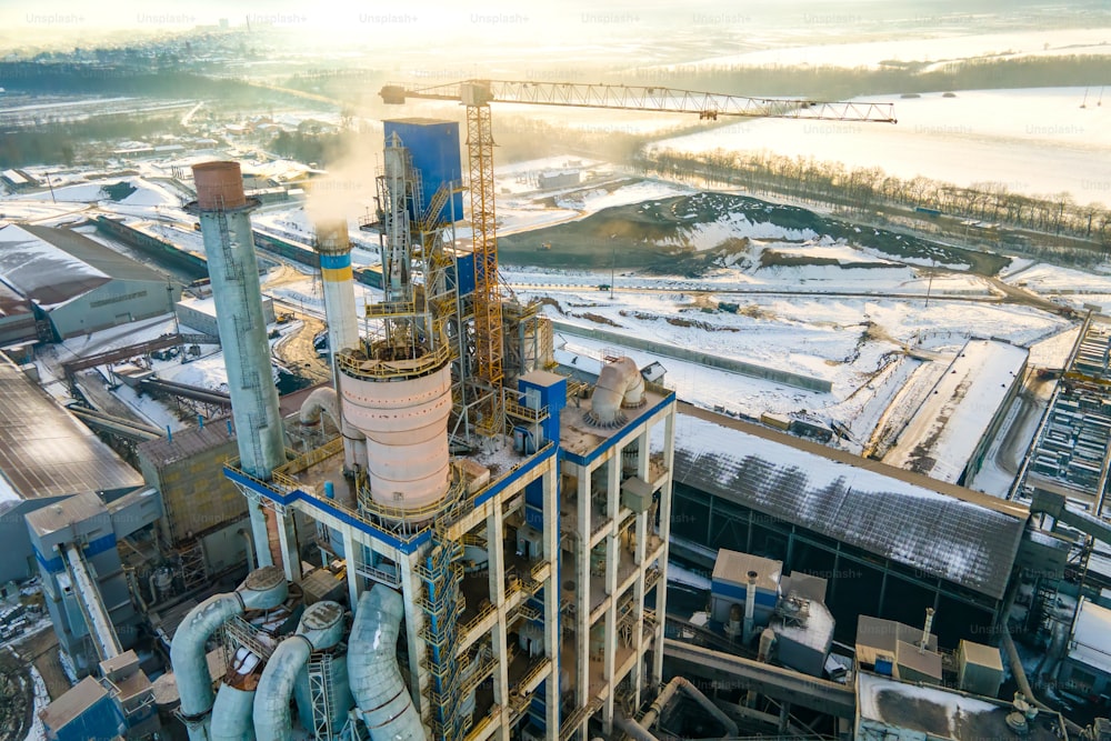 Vista aerea di cementeria con alta struttura di fabbrica e gru a torre in zona di produzione industriale.