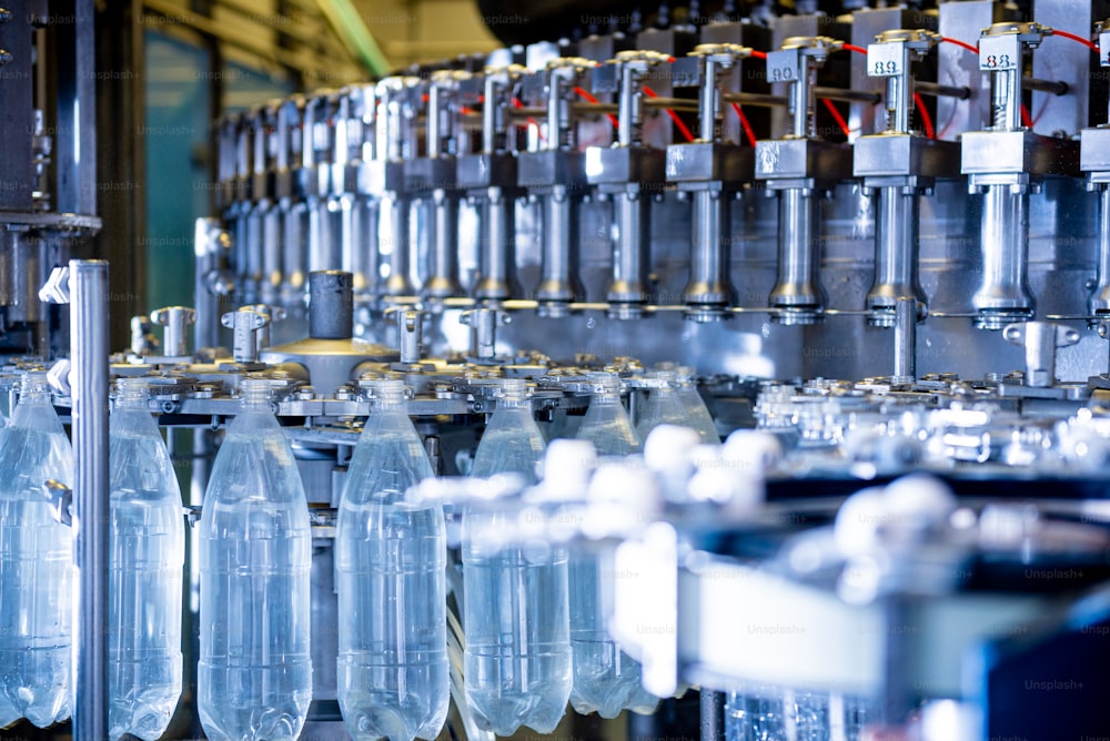Máquina de enchimento automática despeja água em garrafas PET de plástico na moderna fábrica de bebidas