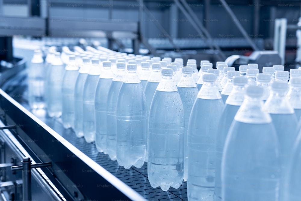 Cinta transportadora con botellas de agua potable en una moderna planta de bebidas