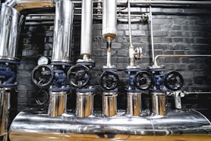 The valves and pipes at a craft modern brewery wall.