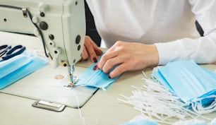 Woman sew the facial medical at sewing machine. Coronavirus pandemia. Diy protective mask against virus.