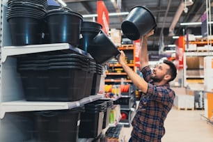 a man in a construction hypermarket chooses construction buckets.