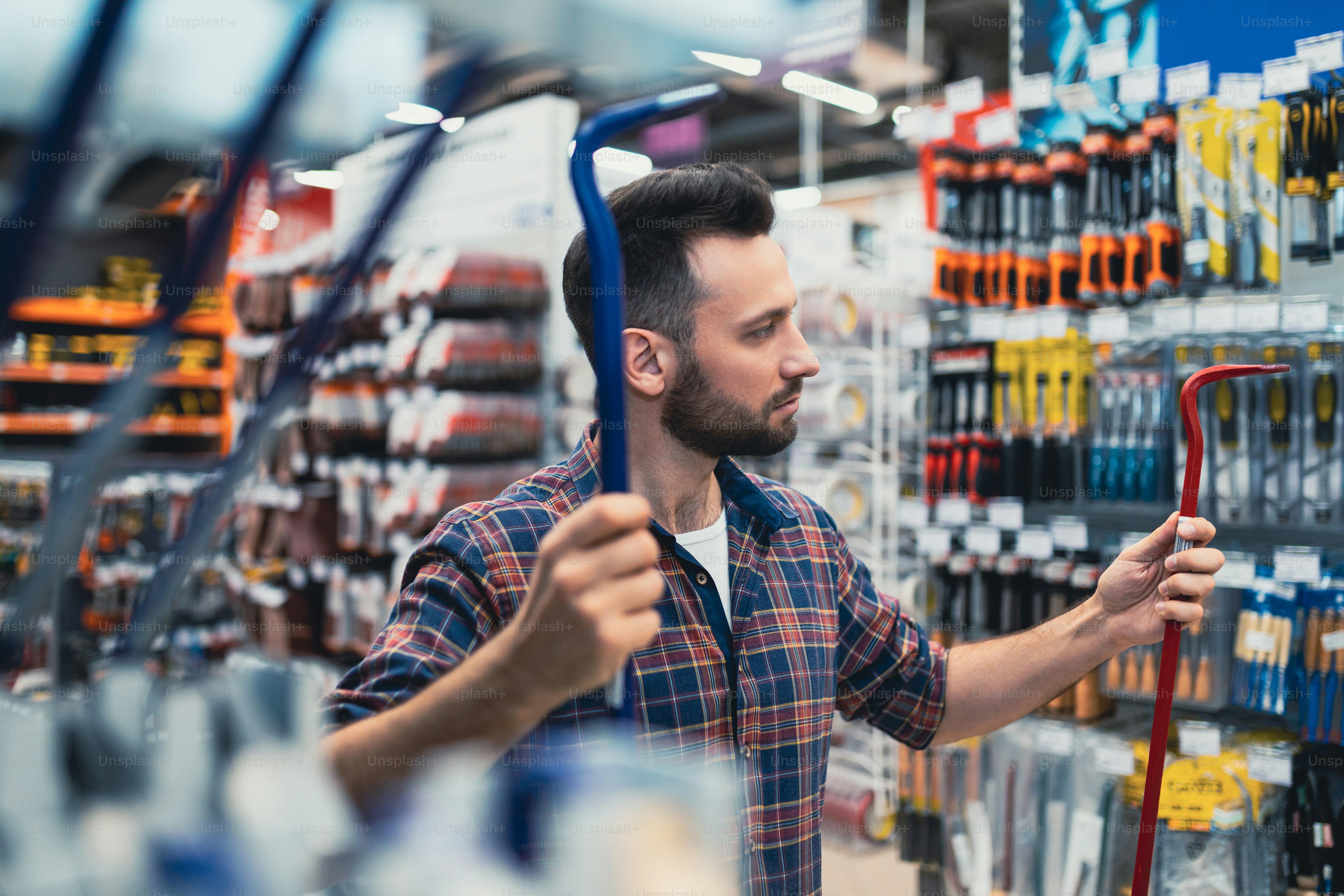 a male customer in a hardware store compares two nail pullers.