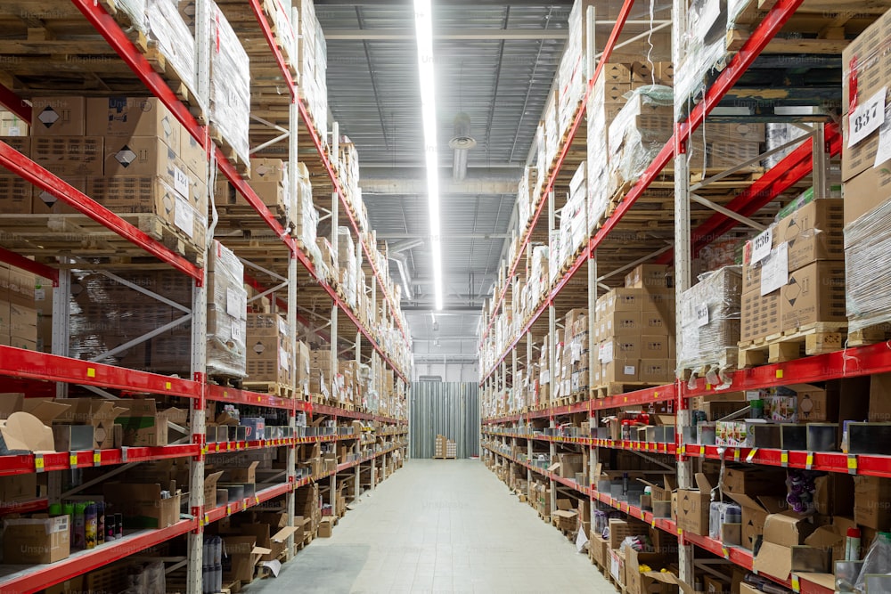 interior of a huge warehouse with long red racks and cardboard boxes.