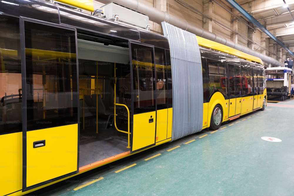 One working day of modern automatic bus manufacturing with unfinished cars workers in protective uniform automotive industry