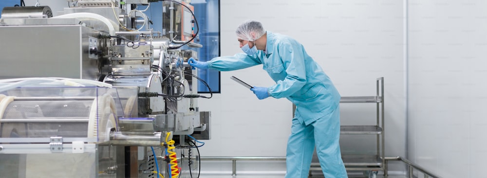widescreen photo of scientist standing abd working with manufacture machine