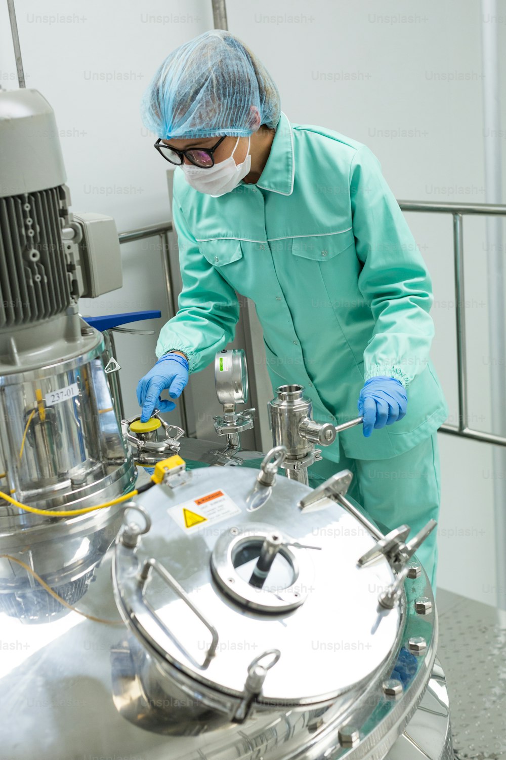 Wissenschaftler im blauen Laboranzug bei der Arbeit mit Stahlkompressortank