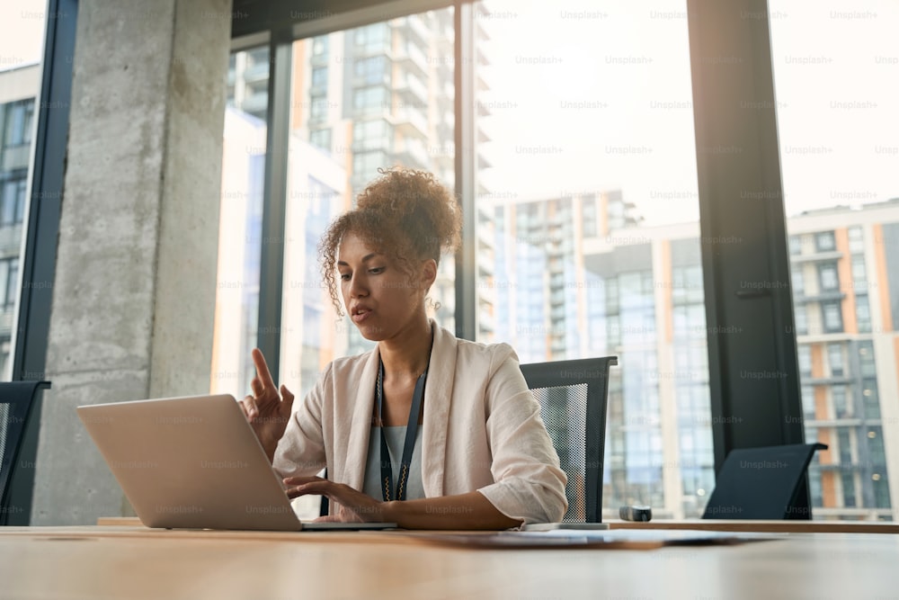 Waist-up portrait of serious focused young female entrepreneur working on portable computer