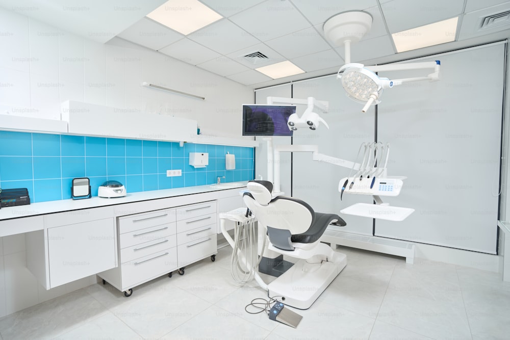 Spacious dentist office with empty leather dental chair and bright overhead lighting