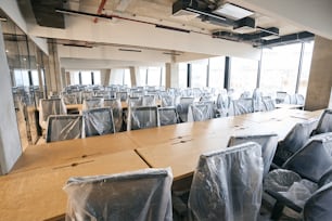Großzügiger moderner Coworking-Bereich nach Desinfektion und Generalreinigung, riesige Fenster, saubere Büroräume mit überdachten Möbeln, High-Tech-Design