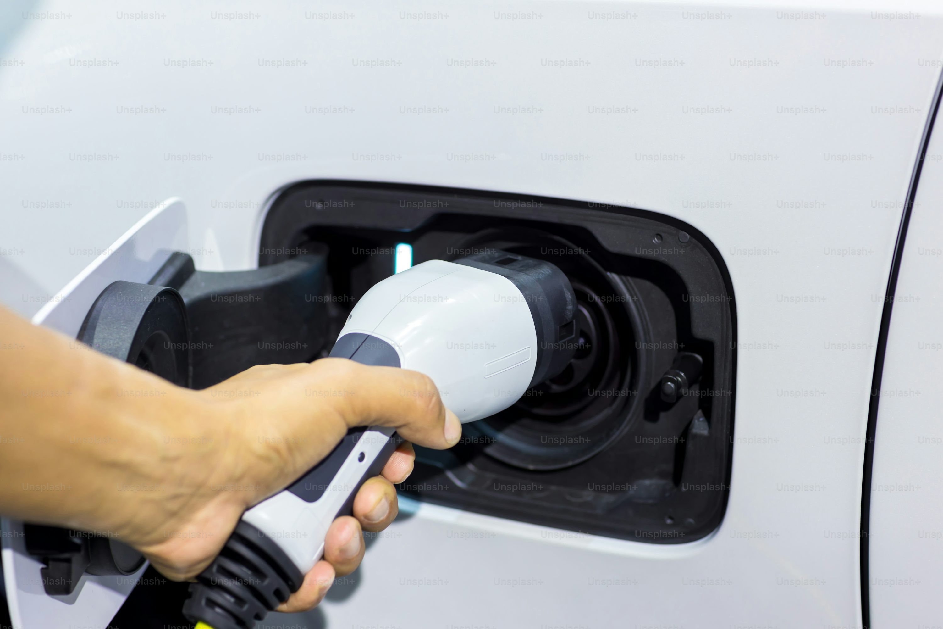 Hand holding Electric car charger. Electric Vehicle EV Charging station and Charger. Human hand is holding Electric Car Charging connect to Electric car.