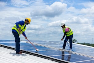ブラシと水でソーラーパネルを掃除する労働者。太陽エネルギー電力計画でソーラーモジュールを清掃する労働者