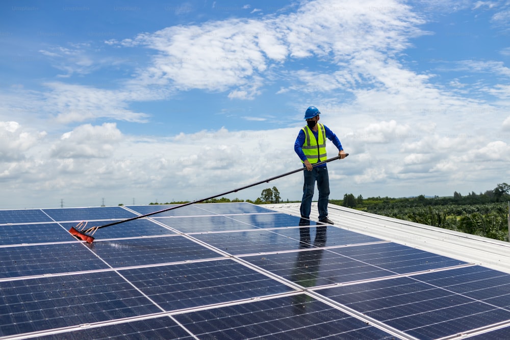 Worker Cleaning solar panels with brush and water. Worker cleaning solar modules in a Solar Energy Power Plan