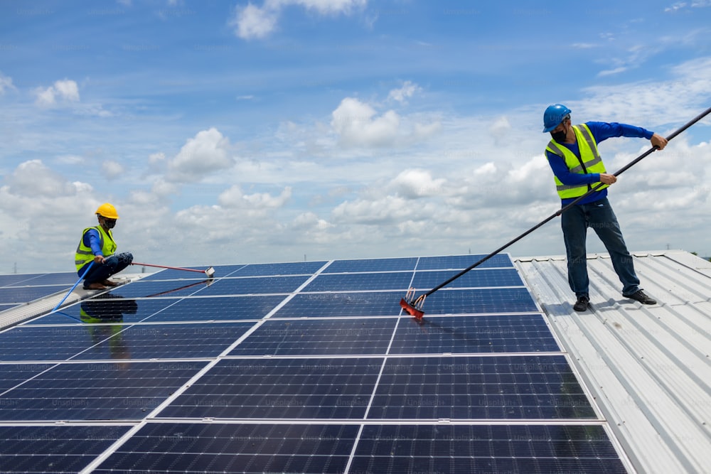 Worker Cleaning solar panels with brush and water. Worker cleaning solar modules in a Solar Energy Power Plan