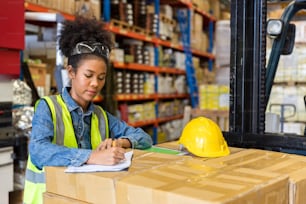 Travailleur afro-américain travaillant dans un entrepôt. Concept de travailleurs industriels et industriels. femme ouvrière détails de commande et vérification des marchandises et des fournitures.