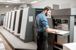 Operador de impresión que trabaja con máquina offset en la fabricación de impresión