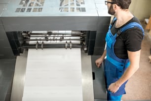 Worker following a printing process on the offset machine at the manufacturing