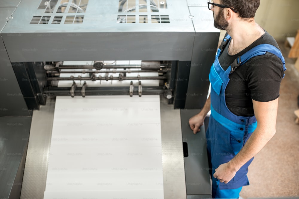 Worker following a printing process on the offset machine at the manufacturing