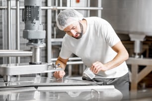 チーズ製造時のステンレスタンクでの牛乳発酵工程中にサプリメントを追加する作業者