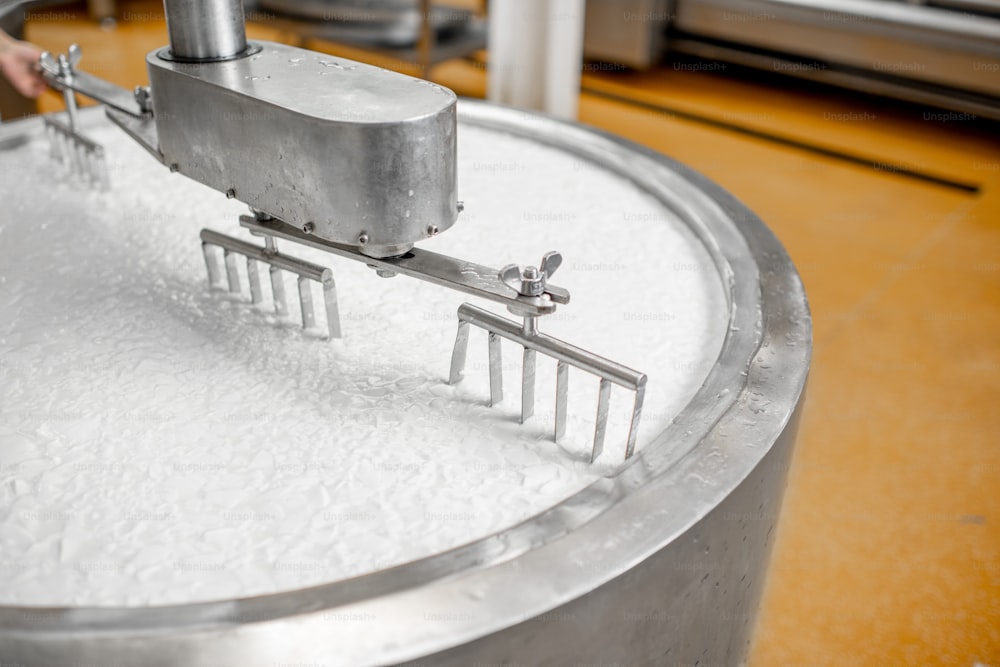 Mistura de leite no tanque inoxidável durante o processo de fermentação na fabricação de queijo