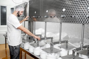 Ouvrier exploitant la machine de presse pressant le fromage à la fabrication