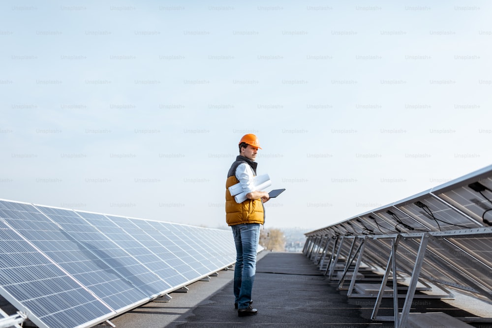 屋上の太陽光発電所で、男性が歩いて太陽光発電パネルを調べる様子。代替エネルギーの概念とそのサービス
