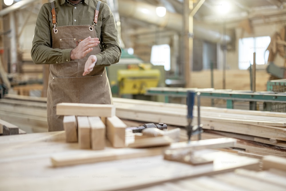 Factory worker shakes sawdust out of his hands with no face. A carpentry employee. Woodworking industry. High quality photo