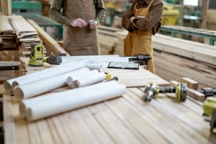 Artigiani che progettano alcuni lavori in legno, disegnando su una tavoletta digitale al banco di lavoro con strumenti e progetti nella falegnameria. Foto di alta qualità