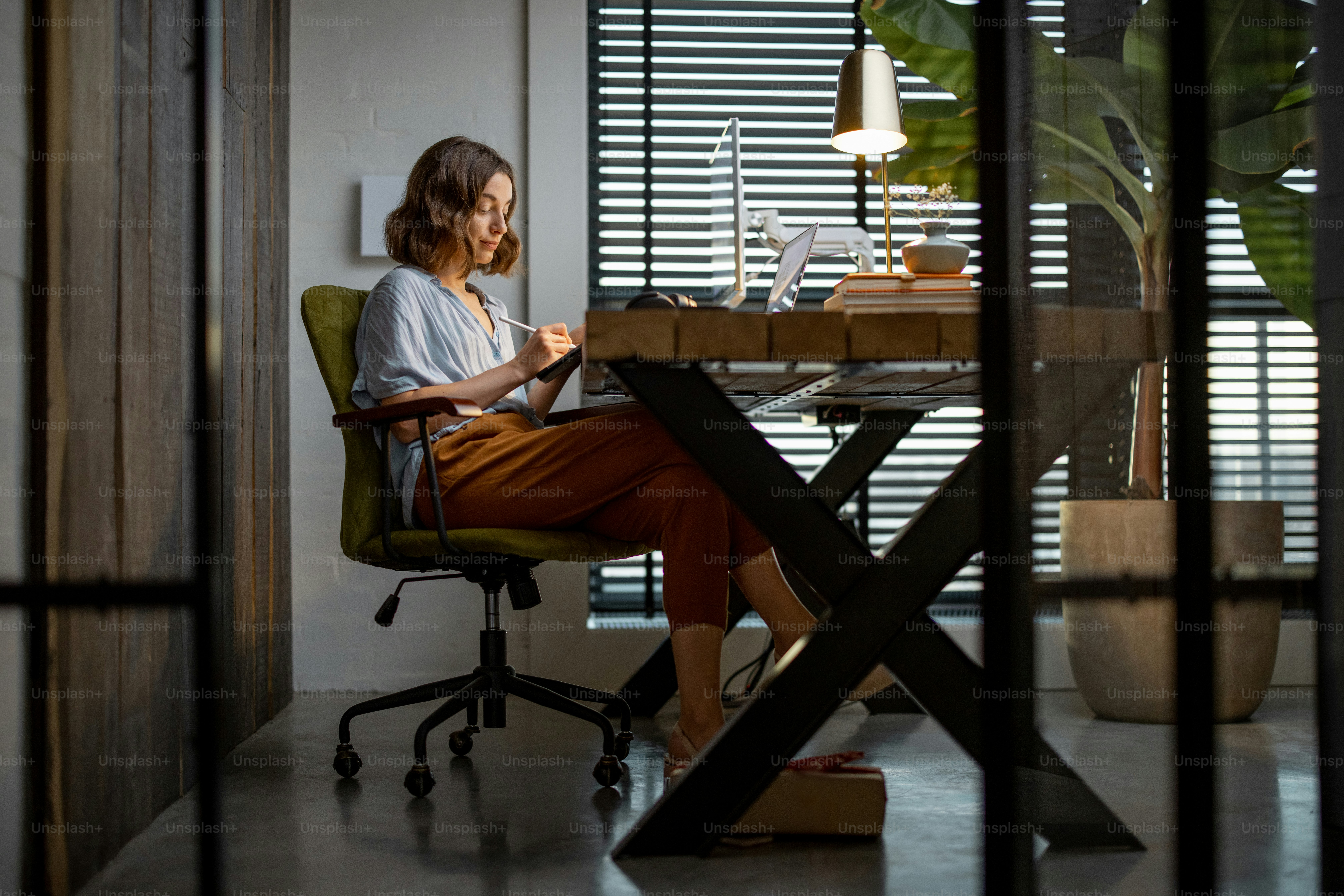 Creative woman working on a touchpad at the cozy and stylish home office. Full shot