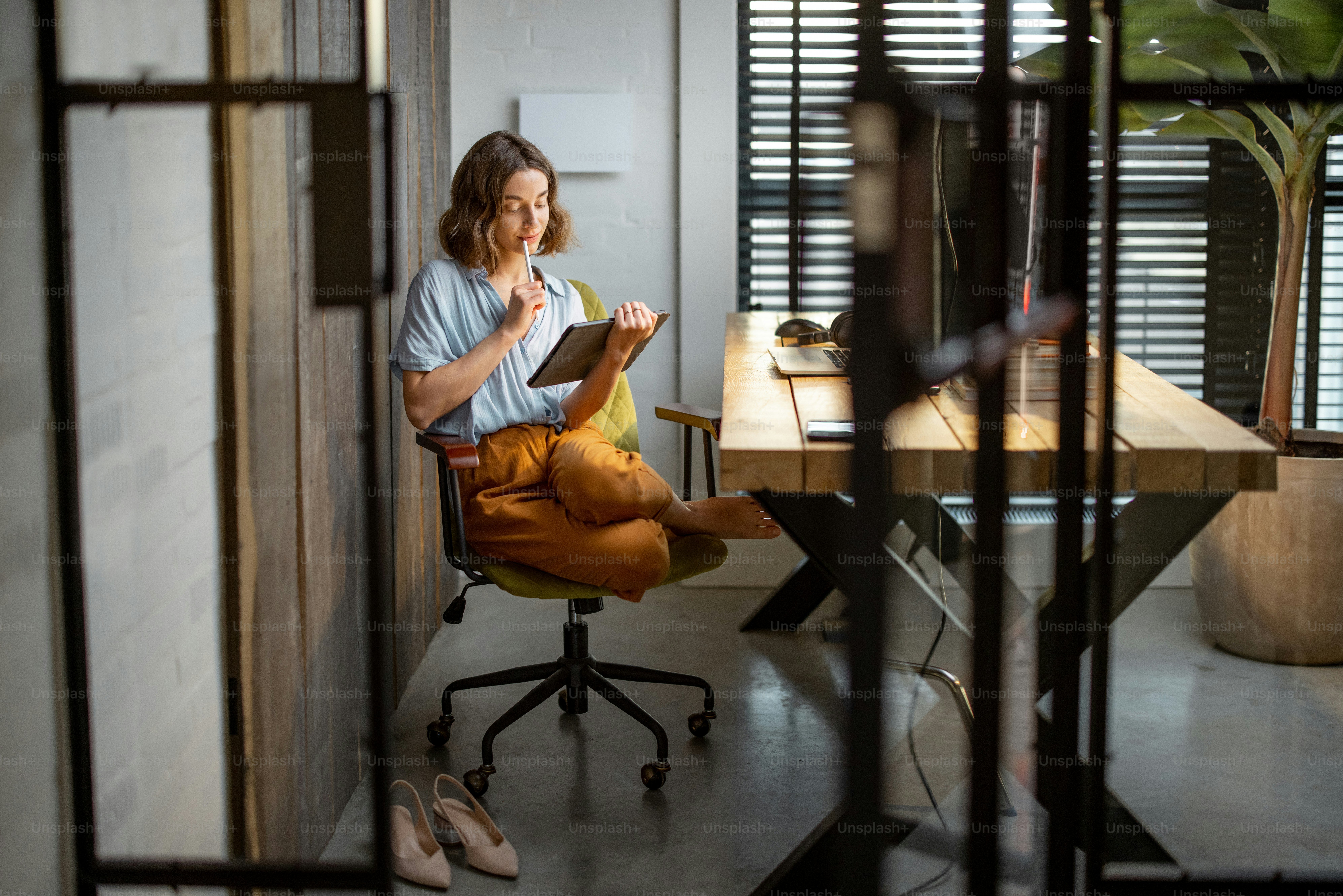 Creative woman working on a touchpad at the cozy and stylish home office. Full shot