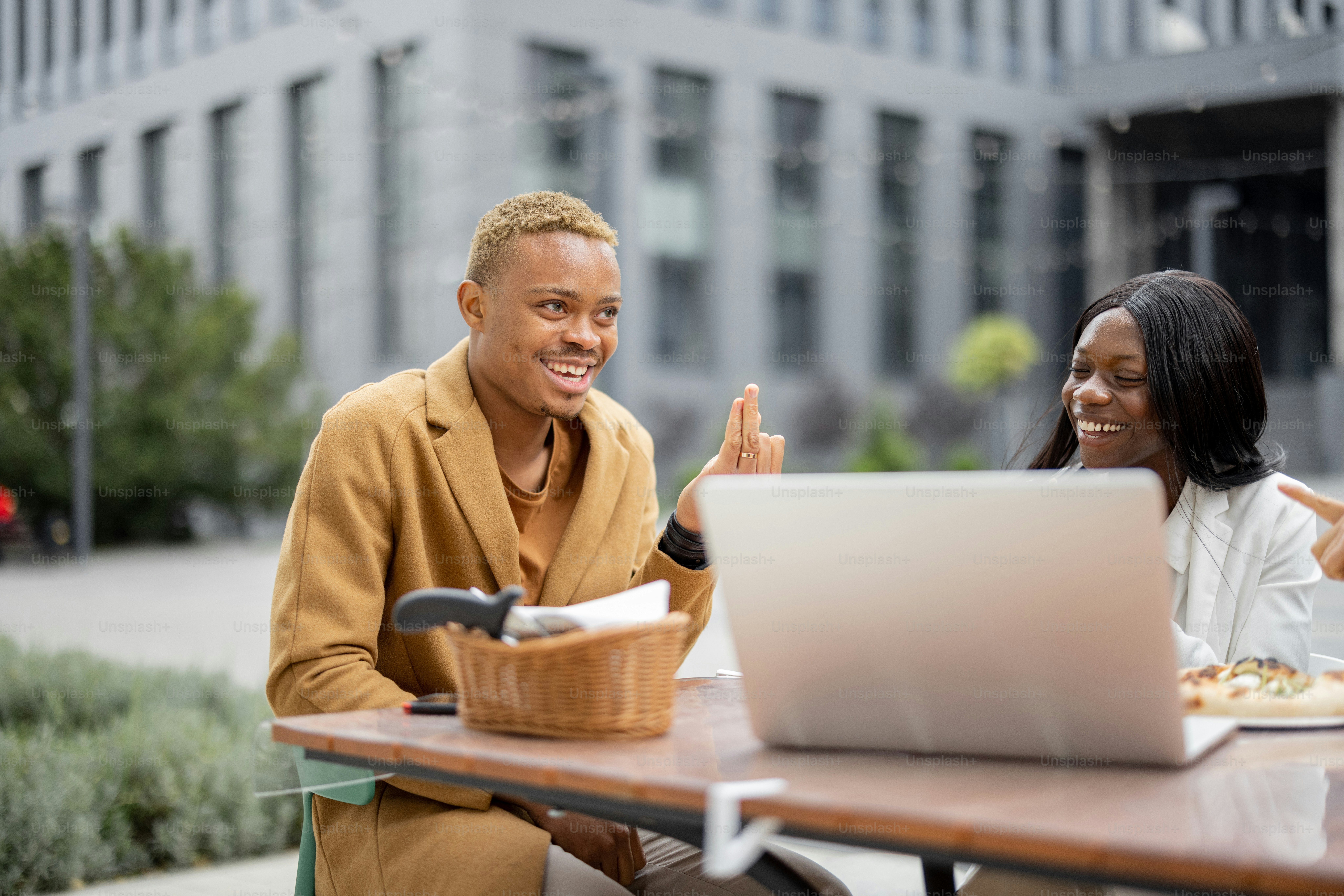 Hombre y mujer jóvenes teniendo una conversación de negocios durante la hora del almuerzo. Equipo de negocios trabajando en una computadora portátil en una cafetería al aire libre. Concepto de teambuilding y evento corporativo. Idea de descanso y ocio en el trabajo