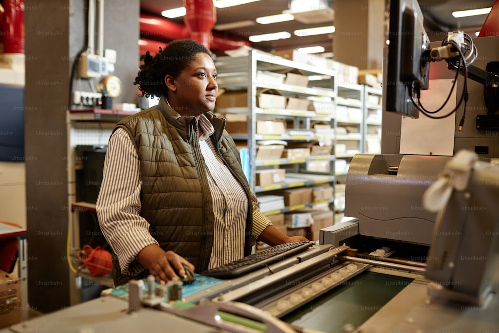 Retrato de una mujer afroamericana operando una máquina de impresión en una fábrica de impresión