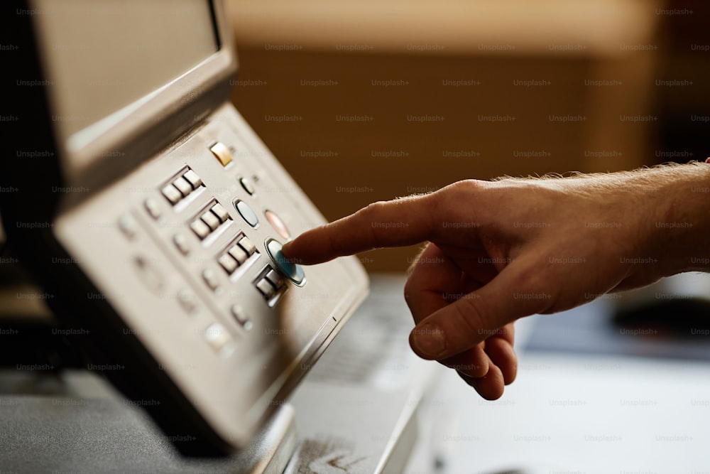 Primer plano de la vista lateral de la mano masculina presionando el botón de inicio en la máquina de impresión, espacio de copia