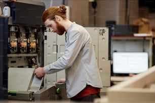 Retrato lateral de un joven barbudo que trabaja en la imprenta y la instalación de máquinas, espacio de copia
