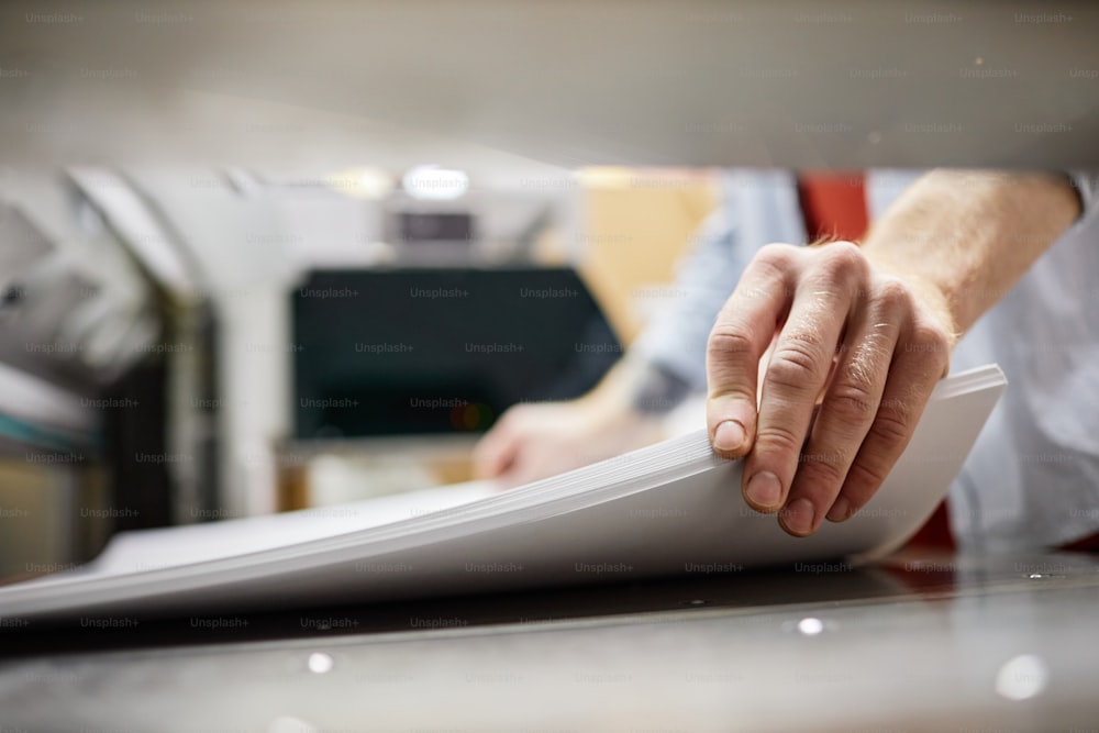 Close up do homem colocando pilha de papel na máquina de impressão na loja de publicação, espaço de cópia