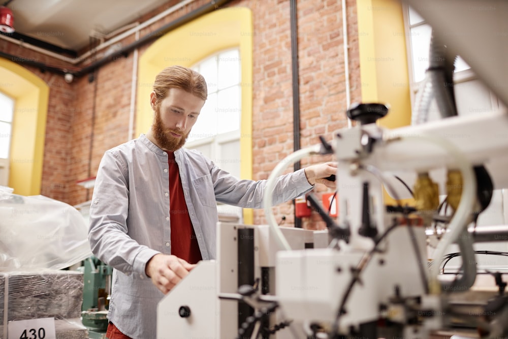 Portrait d’un jeune homme travaillant dans une imprimerie et exploitant une machine d’impression industrielle, espace de copie