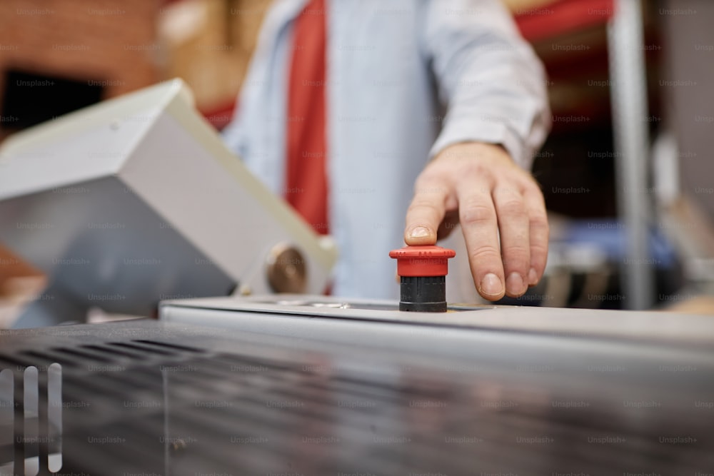 산업 상점에서 인쇄기의 빨간 버튼을 누르는 젊은이의 클로즈업, 복사 공간